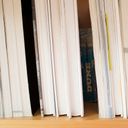 Fore edges of several books on a shelf. Two gaps form the approximation of eleven. In one of the gaps we can see the spine of an old edition of Dune.