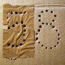 A sheet of box cardboard with a bunch of rough holes shaping the digits five and eight.